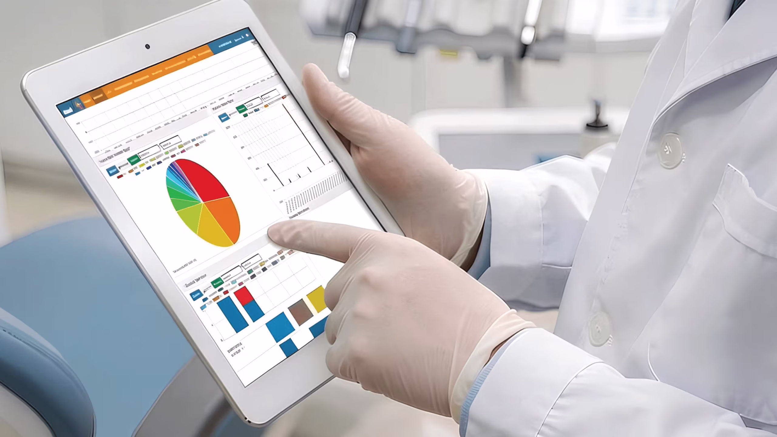 A modern UK dental clinic with a dentist using a tablet, referencing live practice analytics on-screen UK dentist reviewing cloud-based dental practice software on tablet